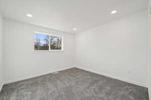 Empty room featuring dark carpet and recessed lighting