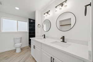 Bathroom with double vanity, light wood-type flooring, a shower, and recessed lighting