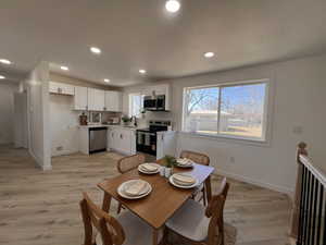 Dining space featuring light wood-type flooring, recessed lighting, and a textured ceiling