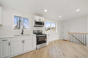Kitchen featuring stainless steel appliances, light wood-style floors, recessed lighting, white cabinets, and light stone counters