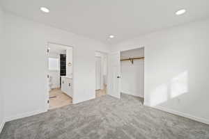 Unfurnished bedroom with light carpet, a closet, recessed lighting, and ensuite bath