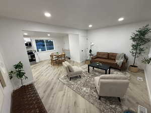 Living area with light wood finished floors and recessed lighting