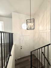 Stairs with wood finished floors and hanging lights