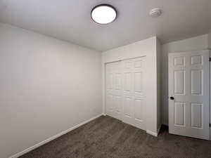 Unfurnished bedroom featuring a closet and dark colored carpet