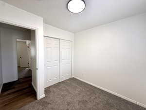 Unfurnished bedroom featuring dark carpet and a closet