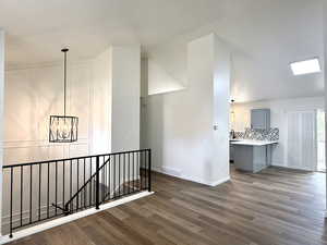 Hall featuring an upstairs landing, dark wood-style flooring, and a chandelier