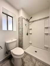 Full bathroom featuring toilet and a stall shower