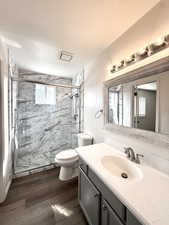 Full bathroom featuring vanity, a marble finish shower, dark wood-type flooring, and a textured ceiling