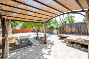 Fenced backyard featuring a patio, a wooden deck, and a pergola