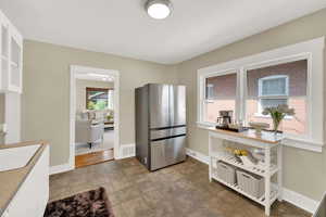 Kitchen featuring freestanding refrigerator, white cabinets, glass insert cabinets, and light countertops