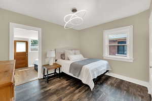 Bedroom with dark wood-type flooring, multiple windows, and suspended lighting