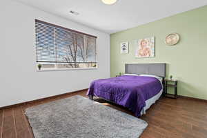 Bedroom with dark wood-style flooring and baseboards