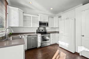 Kitchen with stainless steel appliances, white cabinetry, open shelves, dark countertops, and recessed lighting