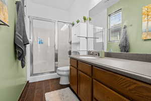 Full bathroom with vanity, a stall shower, and dark wood-type flooring