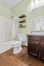 Full bath featuring vanity, shower / bathtub combination with curtain, and dark wood-style flooring