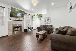 Living room featuring dark wood finished floors, a fireplace, and recessed lighting