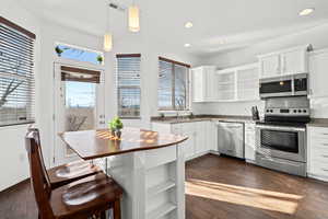 Kitchen featuring open shelves, stainless steel appliances, and white cabinetry