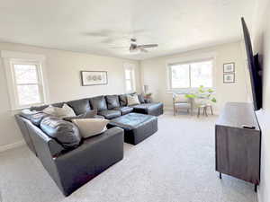 Upstairs living room featuring light carpet, a ceiling fan, and lots of natural light