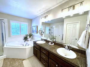 Master bath featuring double vanity, separate shower, soaker tub, plantation shutters, and tile flooring