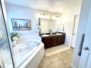 Bathroom with double vanity, soaker tub plantation shutters, and tile flooring