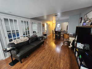 Living room featuring dark wood-type flooring, french doors, and a textured ceiling