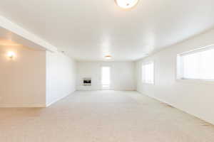 Unfurnished living room featuring light colored carpet, a fireplace, and heating unit