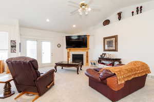 Carpeted living room featuring a ceiling fan, recessed lighting, a tiled fireplace, and lofted ceiling