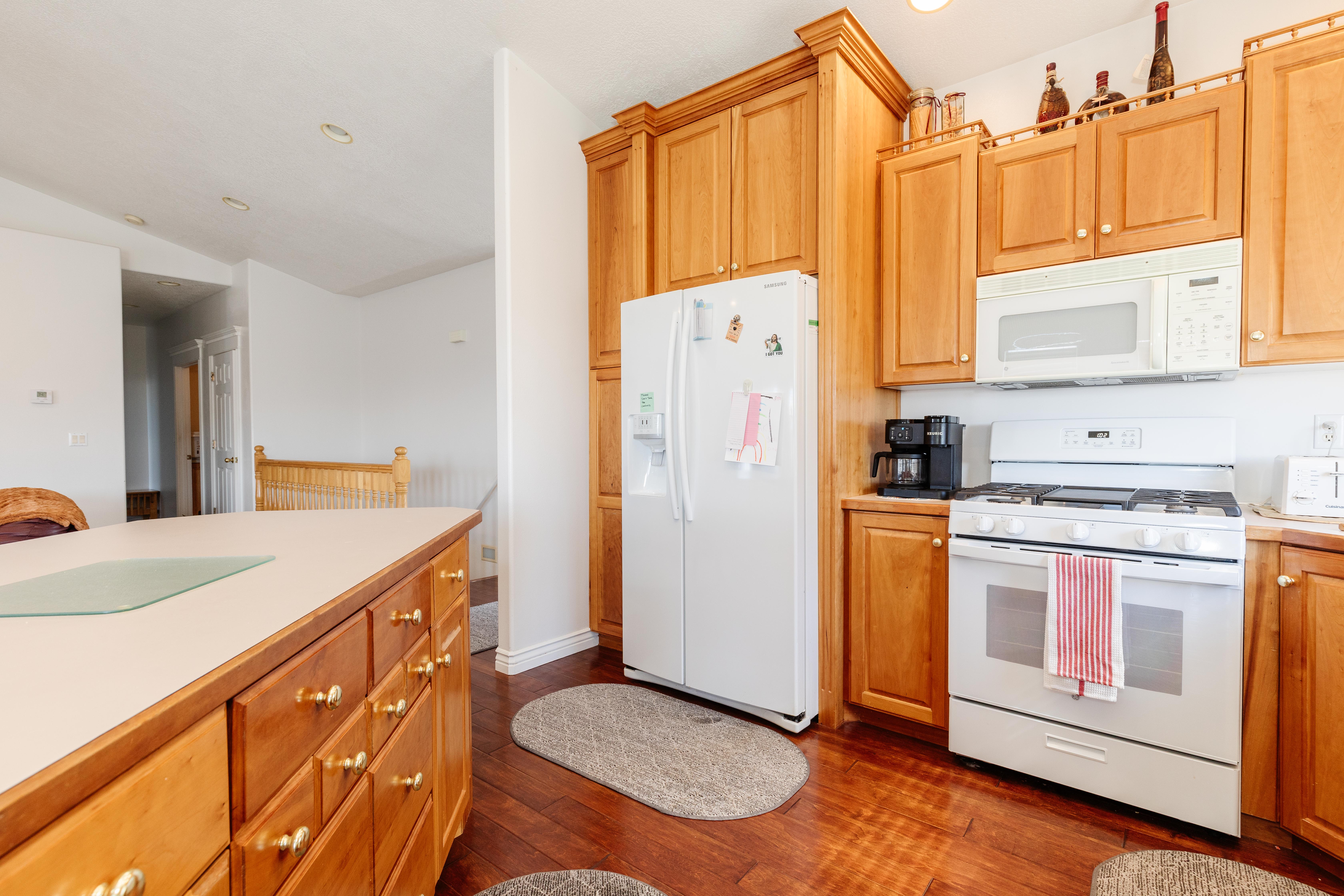 Kitchen featuring white appliances, light countertops, dark wood finished floors, vaulted ceiling, and wood finish cabinetry