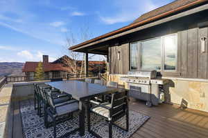 Wooden terrace featuring outdoor dining space, a mountain view, and area for grilling
