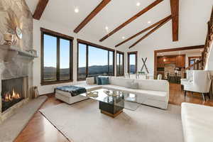 Living room featuring a mountain view, wood finished floors, a high end fireplace, recessed lighting, and vaulted ceiling