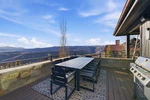 Wooden deck with a mountain view, outdoor dining area, and area for grilling