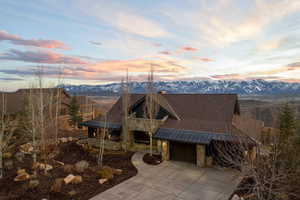 View of front of property with stone siding, a standing seam roof, a mountain view, a chimney, and a garage