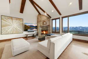 Living area with light wood-style floors, a stone fireplace, and lofted ceiling