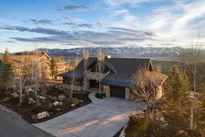 View of front of house featuring stone siding, a standing seam roof, a mountain view, driveway, and a garage