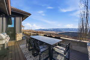 Wooden deck with a mountain view, outdoor dining area, and area for grilling