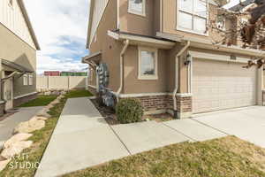 View of front of house with brick siding, an attached garage, stucco siding, and driveway