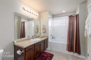 Full bath featuring vanity, shower / tub combo with curtain, and light tile patterned flooring