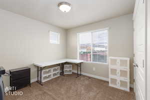 Unfurnished office featuring dark colored carpet and baseboards