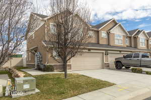View of front of house featuring brick siding, a garage, concrete driveway, and stucco siding