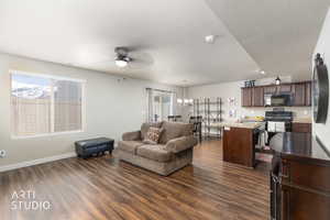 Living area with ceiling fan, dark wood finished floors, healthy amount of natural light, and a chandelier