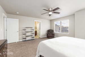 Carpeted bedroom featuring ensuite bathroom and a ceiling fan
