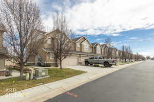 View of front of home featuring a residential view, driveway, brick siding, a garage, and a front lawn