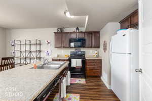 Kitchen featuring black appliances, light countertops, dark wood-type flooring, dark wood finish cabinetry, and a textured ceiling