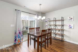 Dining room featuring dark wood-style flooring and a chandelier