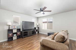 Living room featuring dark wood-style floors and a ceiling fan