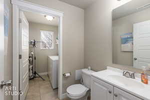 Bathroom with vanity, light tile patterned flooring, and separate washer and dryer