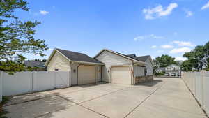 View of property exterior featuring a garage, driveway, a gate, and a shingled roof