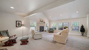 Living room with a glass covered fireplace, carpet flooring, lofted ceiling, and recessed lighting