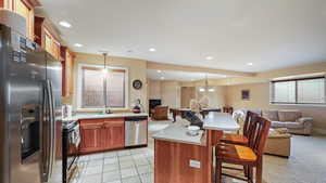 Basement ADU Kitchen with a kitchen bar, stainless steel appliances, open floor plan, wood finish cabinets, and pendant lighting