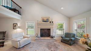 Carpeted living area with a fireplace with raised hearth and vaulted ceiling